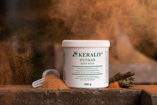 A tin of Keralit hoof bath powder concentrate for horses stands on an iron table surrounded by the powder.