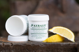 A tin of Keralit Keralysin ointment for the gentle removal of scabs stands on an iron block together with lemons.